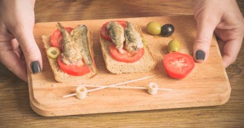 Waitress serve tapas with sardines on wooden plate